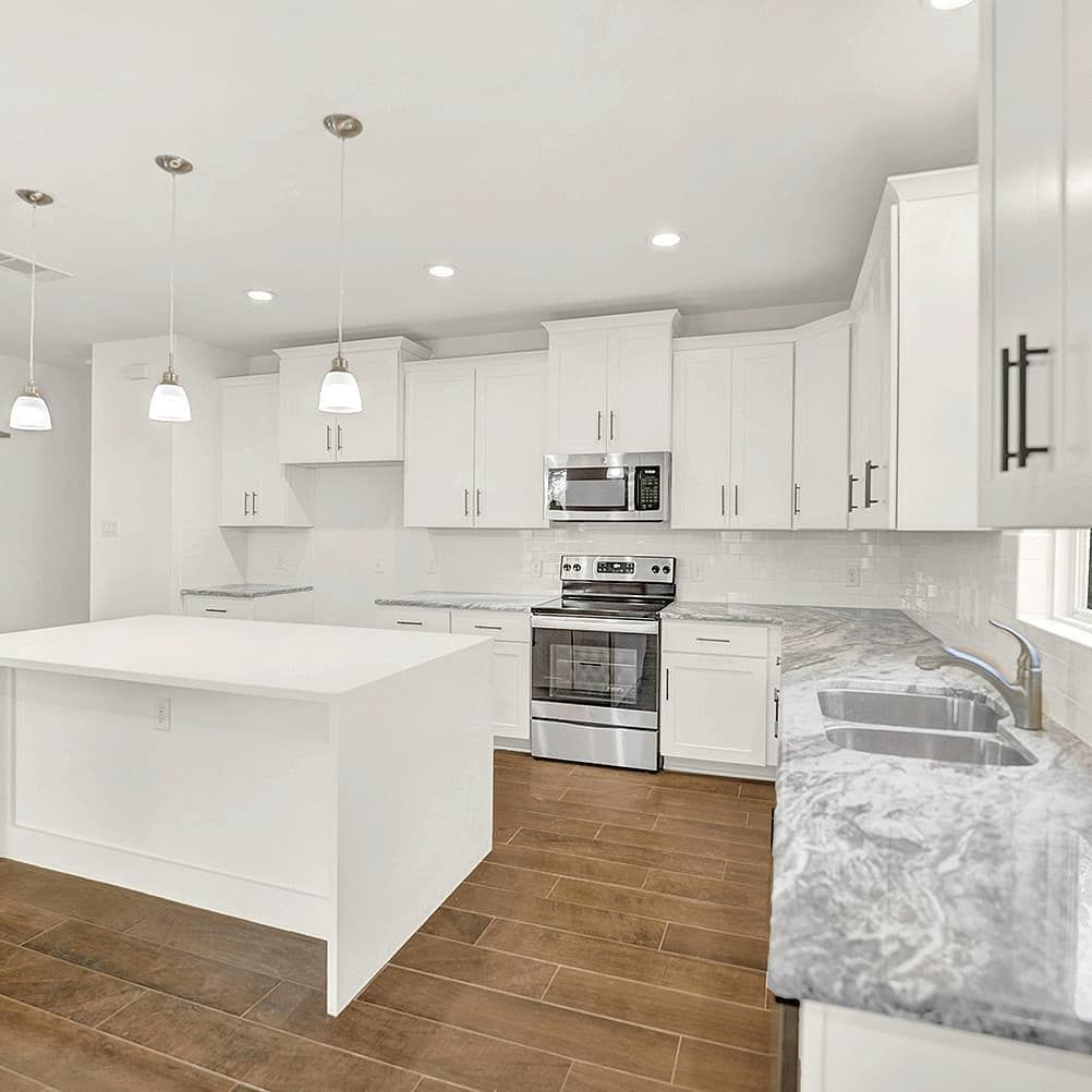Bright white kitchen with island, white cabinets, stainless steel appliances, and dark wood floor.