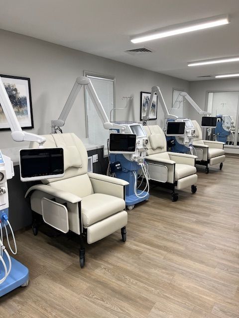 Examination room with dental chairs, screens, and equipment; neutral colors.