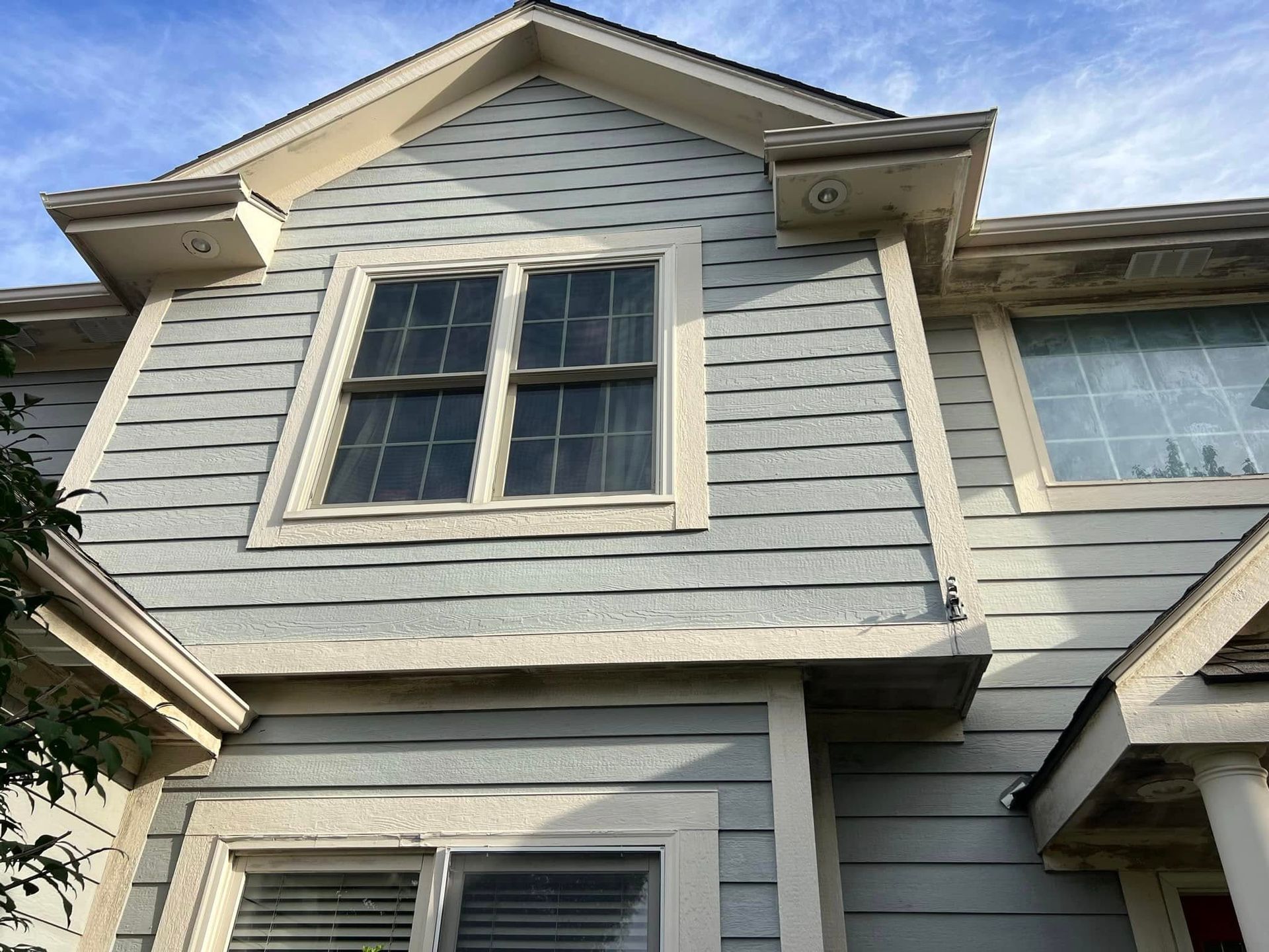 Blue sided building with white trim, windows, and angled roof with eaves.