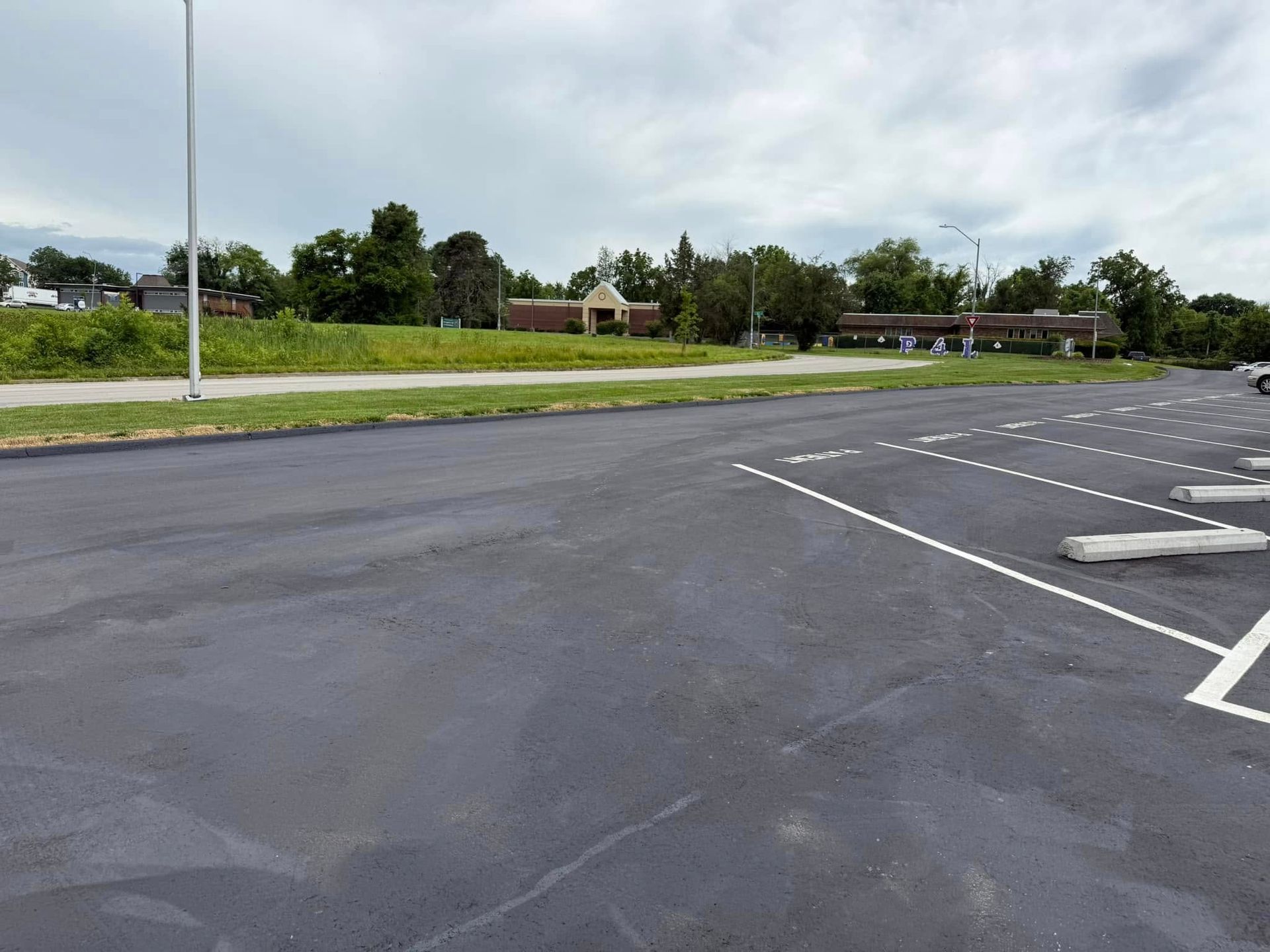 Asphalt parking lot with painted white parking space lines; a low building in the background.