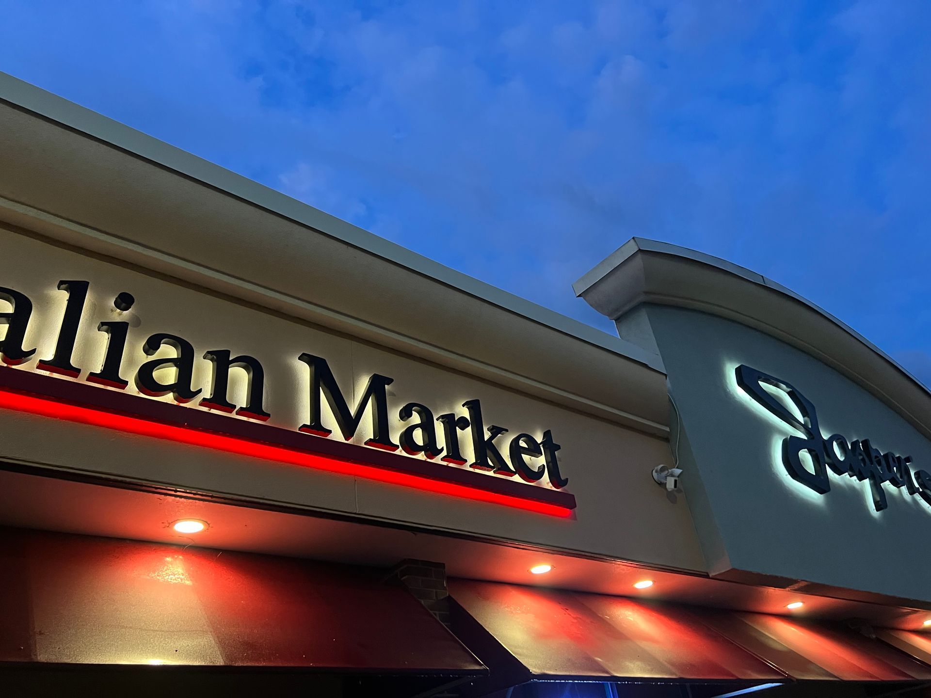 Barn with vintage gas station and Ford Motor Co. signs, blue door, and arched light against a blue sky.
