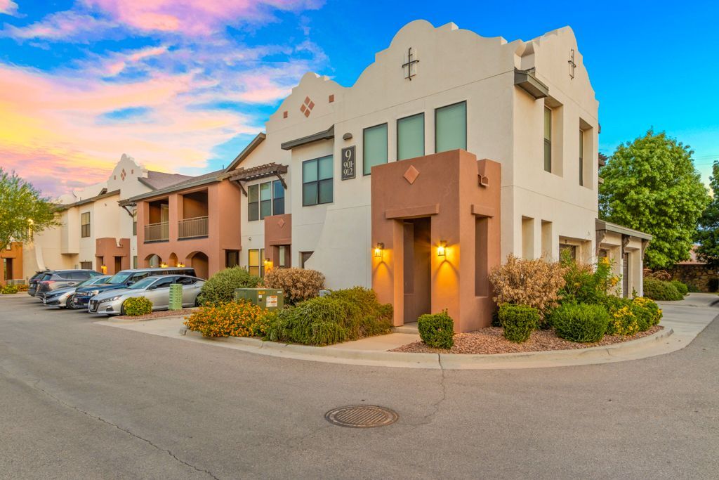 A row of apartment buildings with cars parked in front of them.