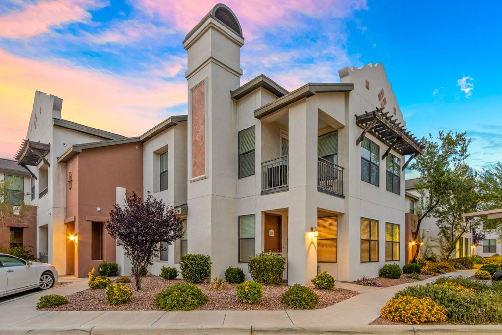 A large apartment building with a car parked in front of it at sunset.