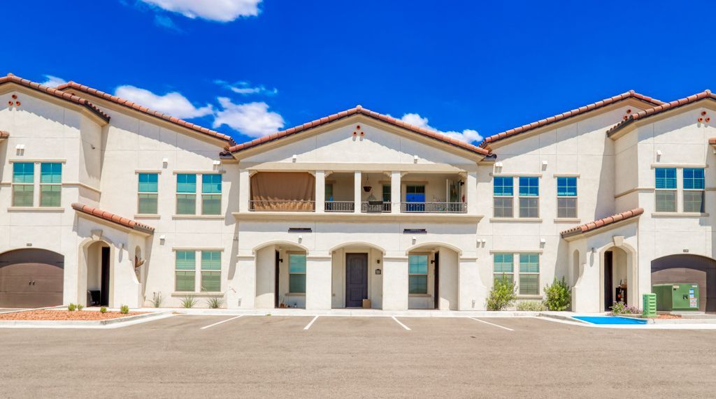 A large white building with a lot of windows and a parking lot in front of it.