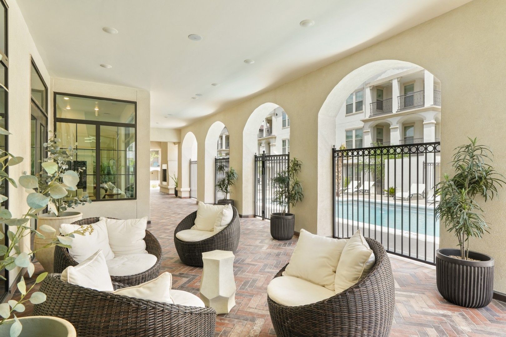 A patio with wicker furniture and a pool in the background.