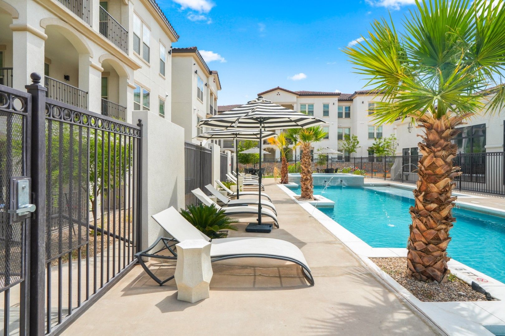 A swimming pool with umbrellas and lounge chairs in front of a building.