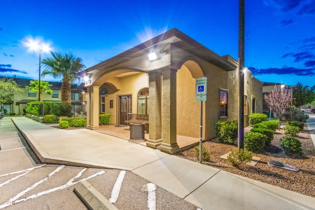 A large building with a parking lot in front of it at night.