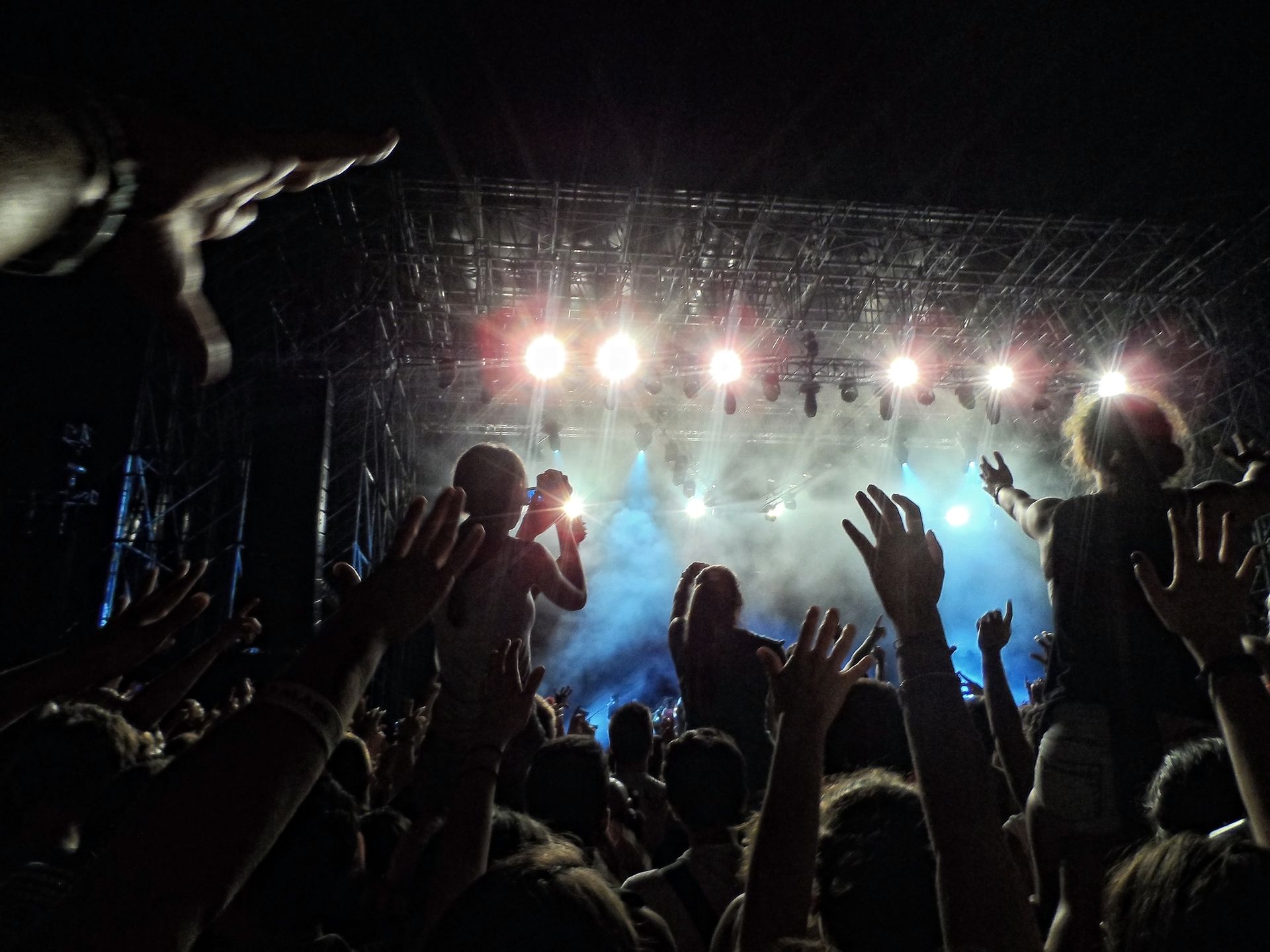 Una folla di persone alza le mani in aria durante un concerto.