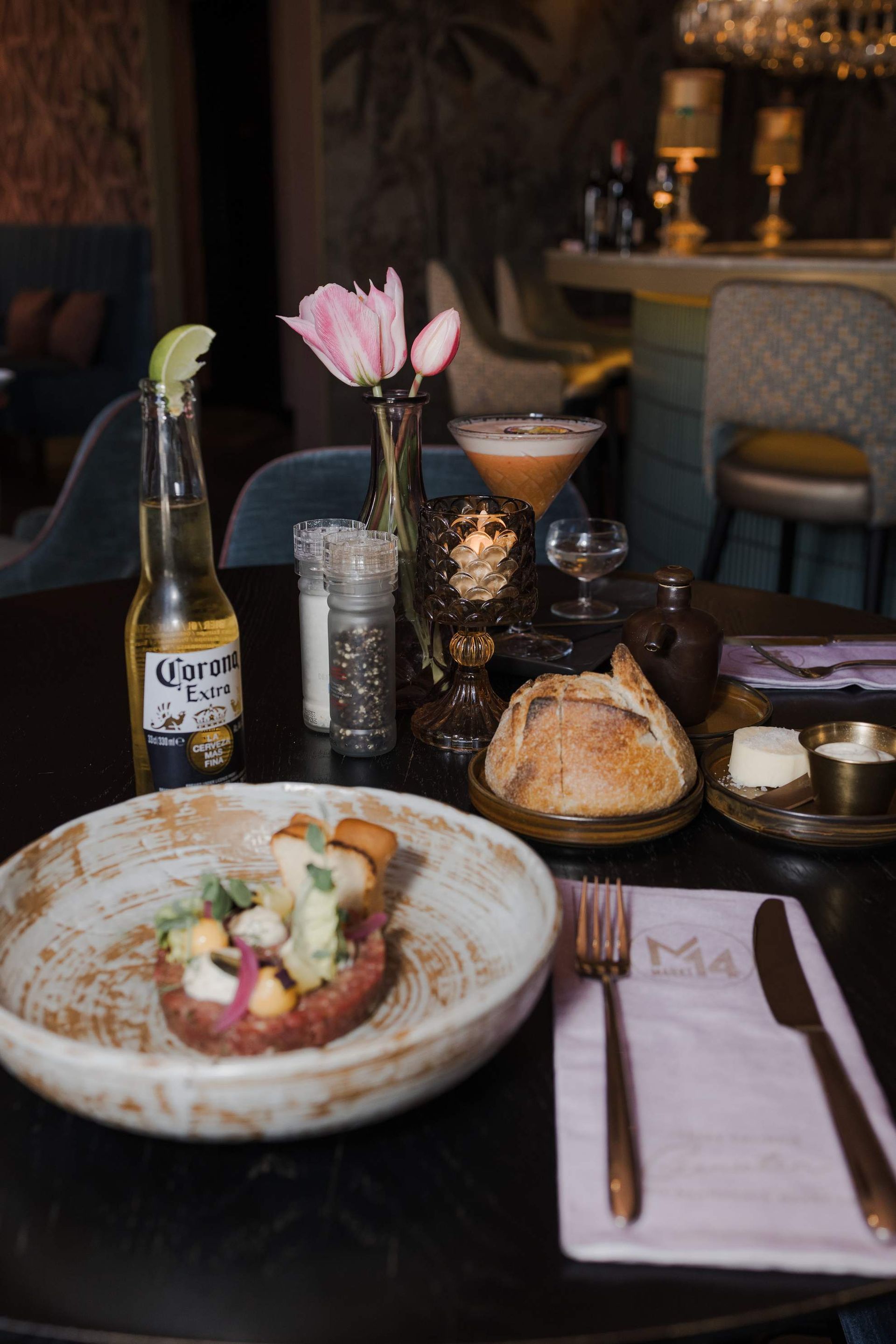 Een barista bedient met een glimlach een espressomachine in een café met roestvrijstalen apparatuur.