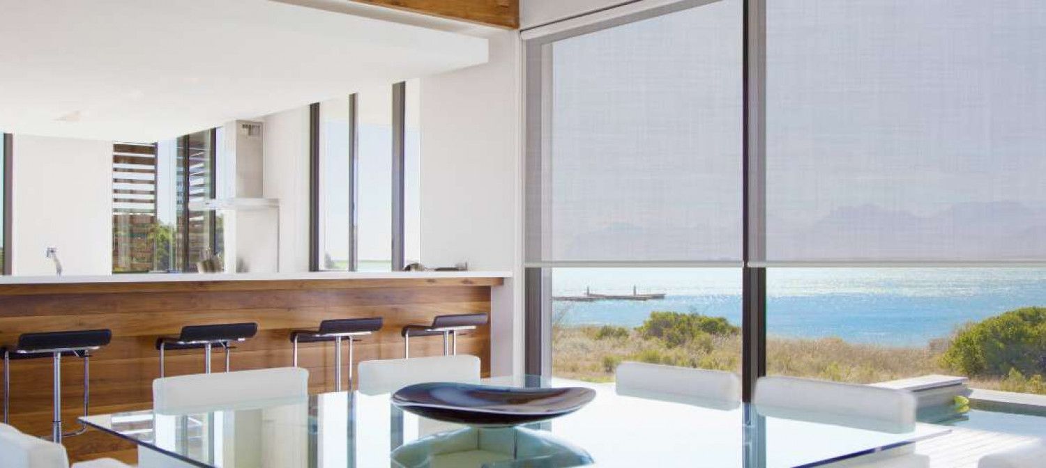 A dining room with a large table and chairs and a view of the ocean