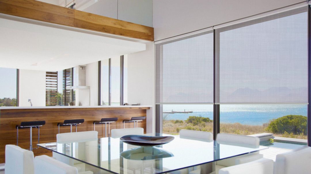 A dining room with a table and chairs and a view of the ocean