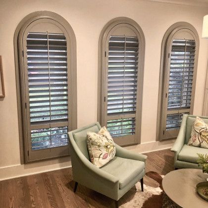 A living room with three arched windows and shutters on the windows