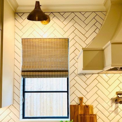 A kitchen with a herringbone tile wall and a window