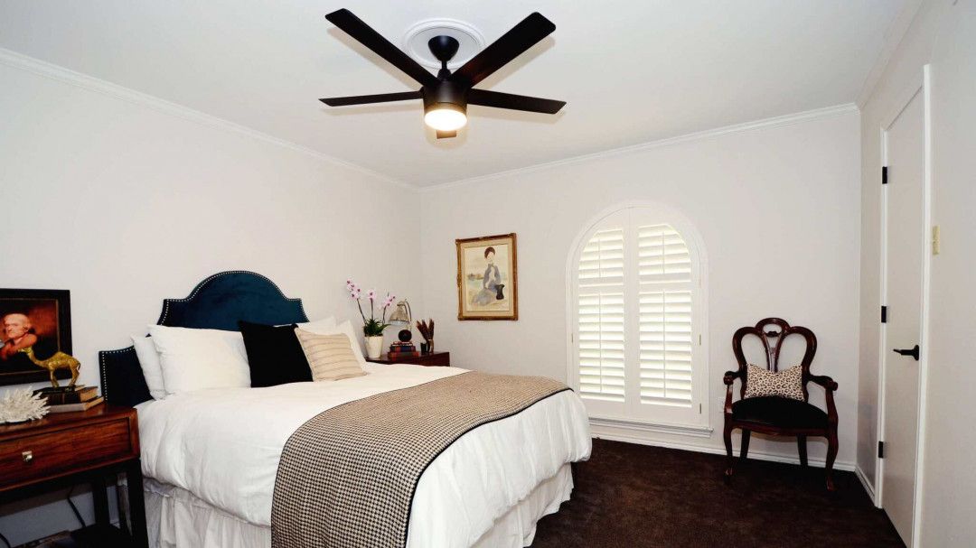 A bedroom with a bed and a ceiling fan