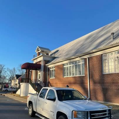 A white truck is parked in front of a brick building.
