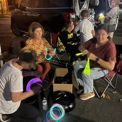 A group of people are sitting around a table with glow in the dark bracelets.