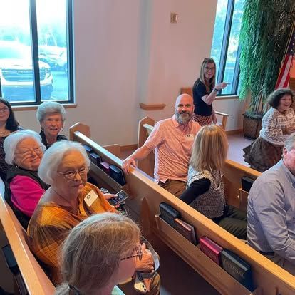 A group of people are sitting in a church talking to each other.