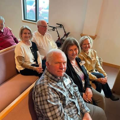 A group of people are sitting on a bench in a room.