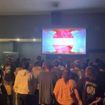 A group of people are watching a movie on a large screen.