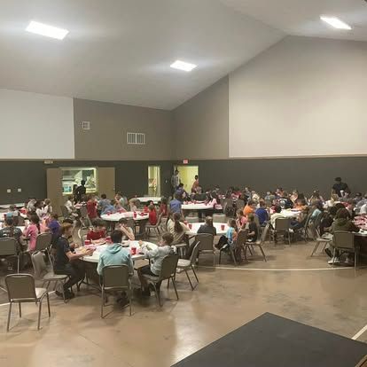 A large group of people are sitting at tables in a large room.