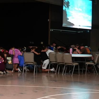 A group of people are kneeling down in front of a large screen.