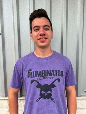 Person in a purple T-shirt standing outdoors in front of a metal wall.