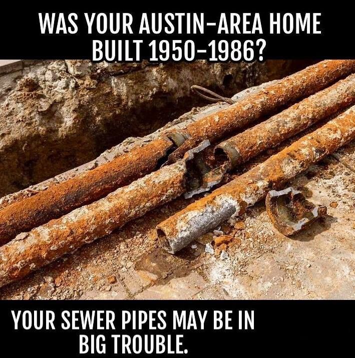 A pile of rusted metal plumbing pipes discarded on a green grassy lawn next to a driveway.