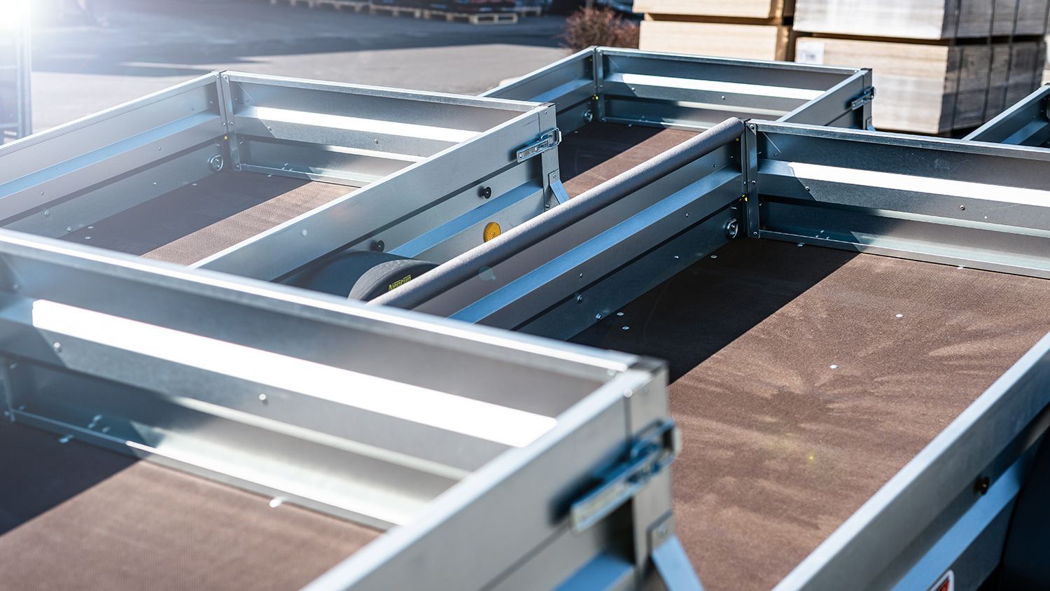 Open utility trailers lined up outdoors, showing metal frames and flat beds ready for hauling. Open utility trailers lined up outdoors, showing metal frames and flat beds ready for hauling.