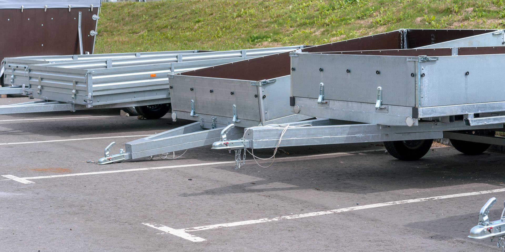 Multiple flatbed trailers for rent lined up in marked parking area on paved surface.