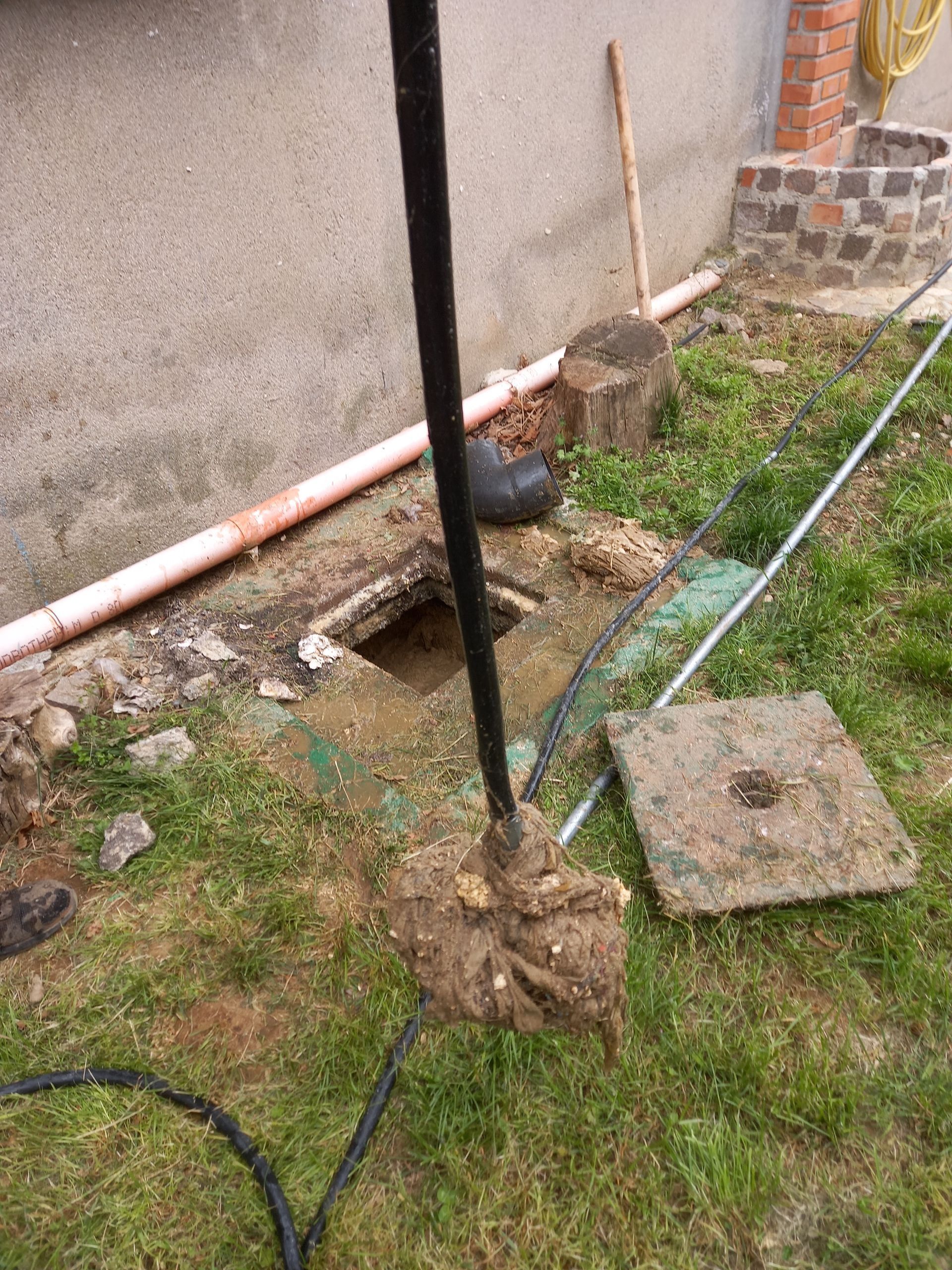 Un pozzo sporco e una tubatura con attrezzature, probabilmente per la manutenzione, in un cortile.