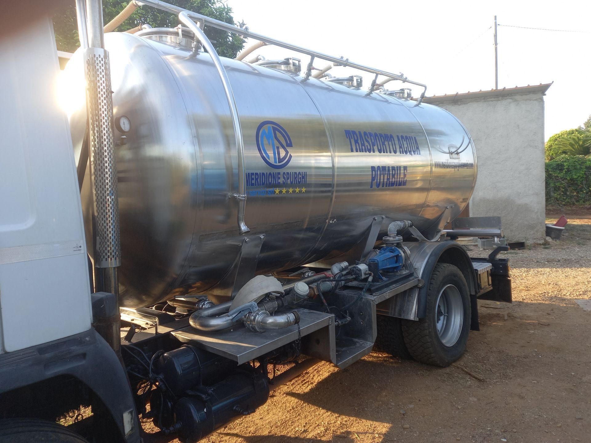 Autocisterna in acciaio inossidabile lucido con scritte blu, parcheggiata all'aperto.