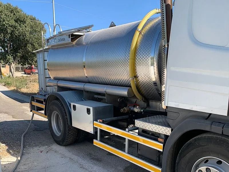 Autocisterna su strada, serbatoio in acciaio inossidabile, tubo giallo, camion argento e bianco.