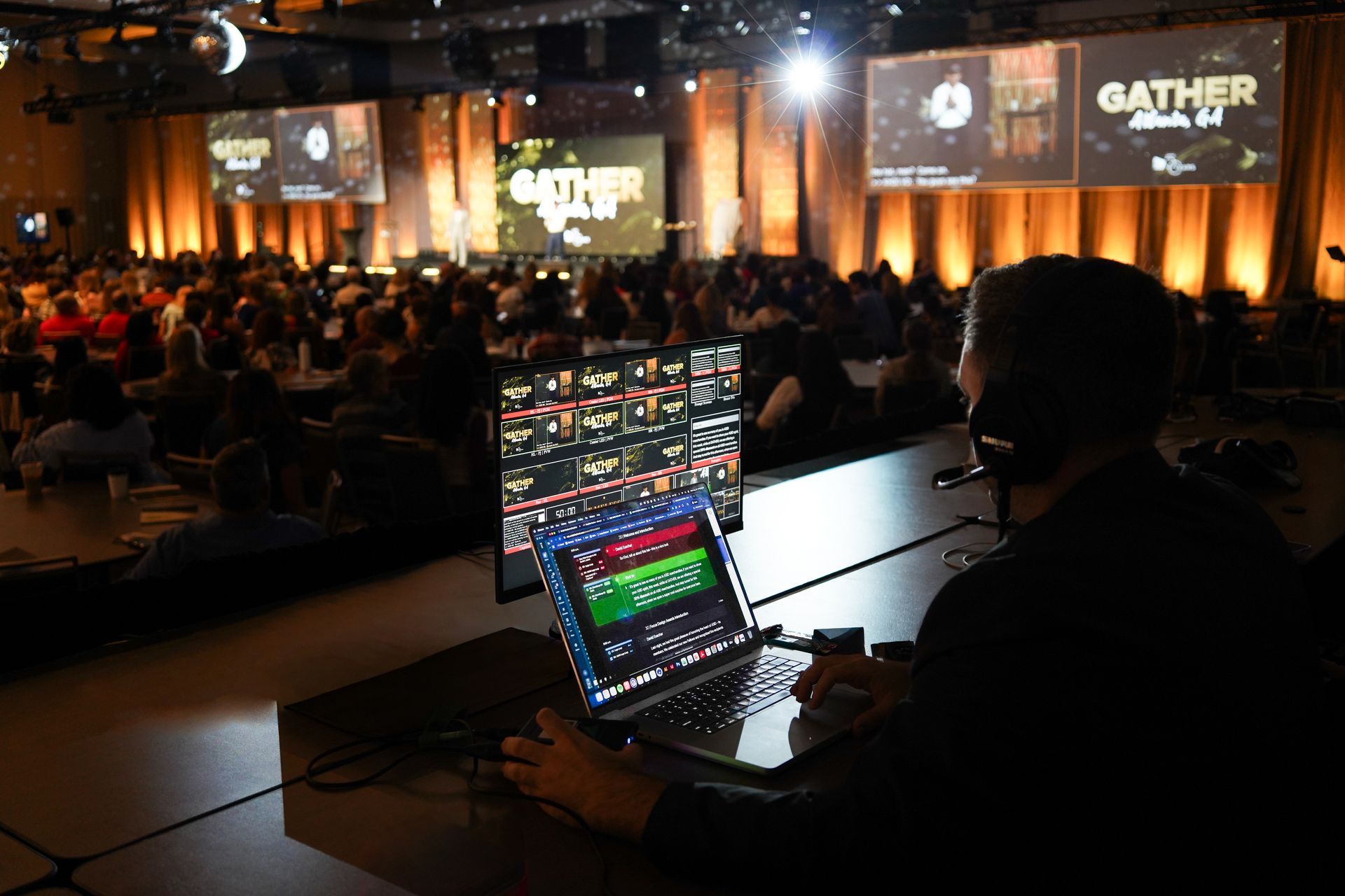 Person operating video equipment at a conference. Large screen with