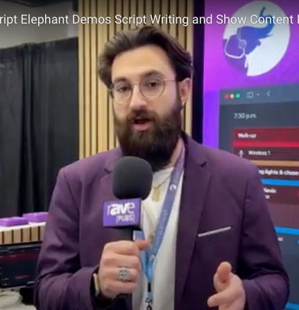 Man with beard in purple blazer holds mic, speaking. Backdrop with Elephant logo and tech.