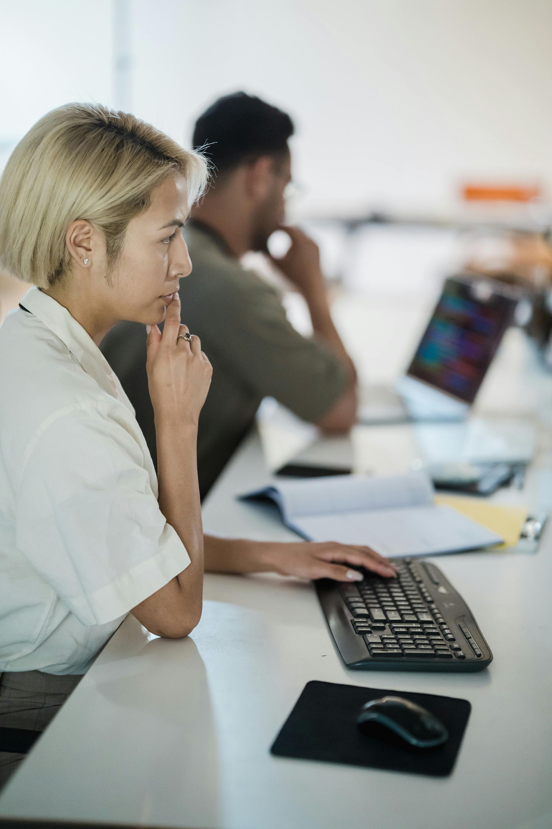 A woman is sitting at a desk using a computer keyboard.