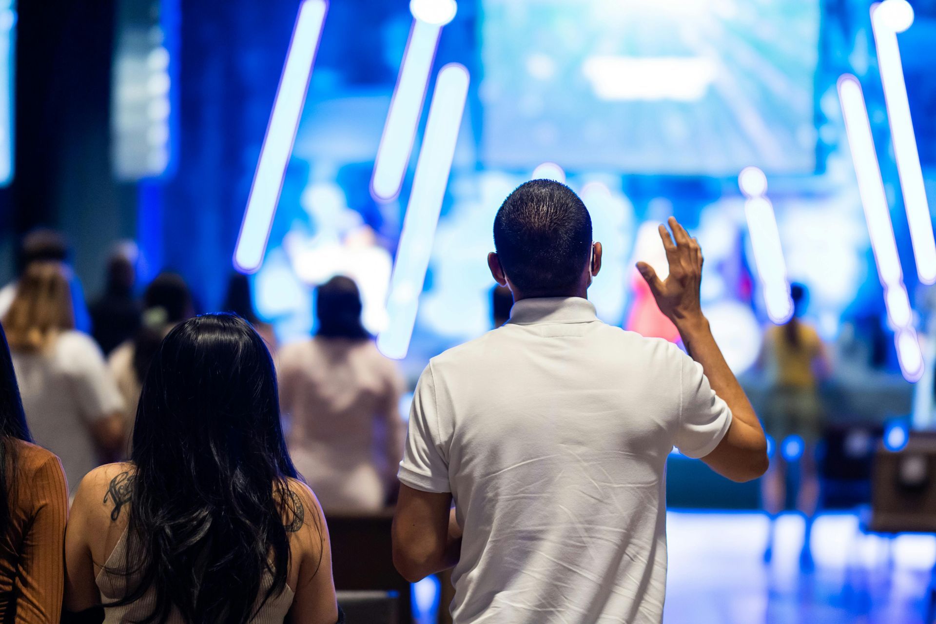 A man is standing in front of a crowd of people at a church or worship event.