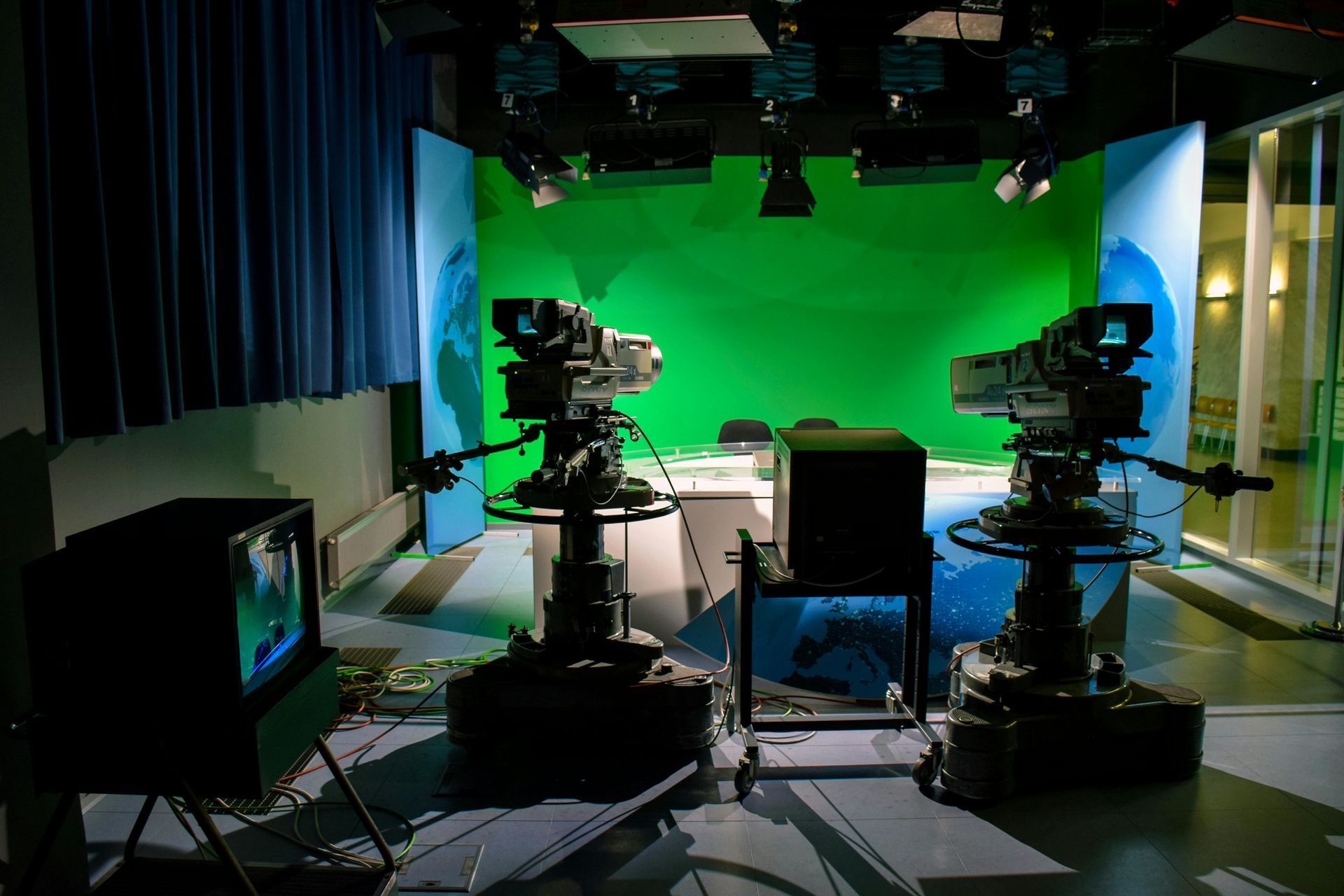Three cameras are in a room with a green screen