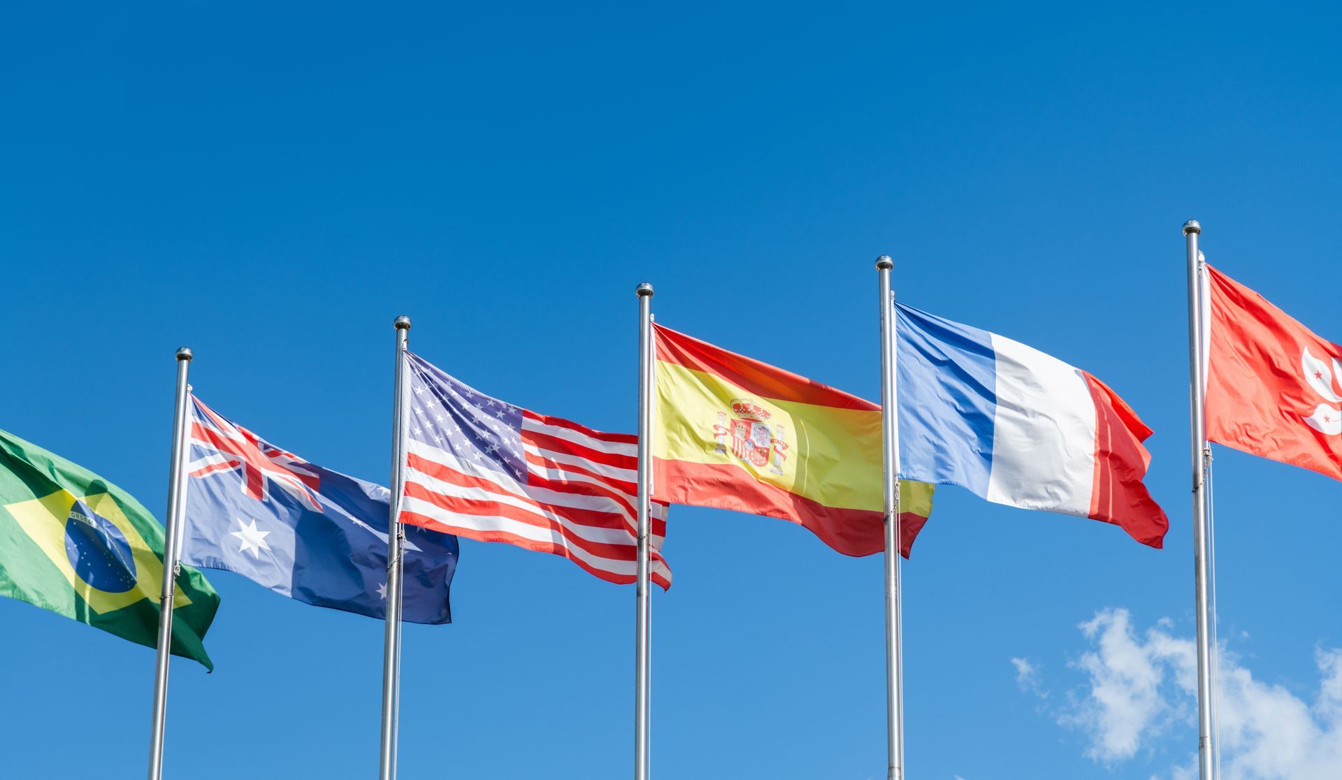A row of international flags waving against a blue sky.
