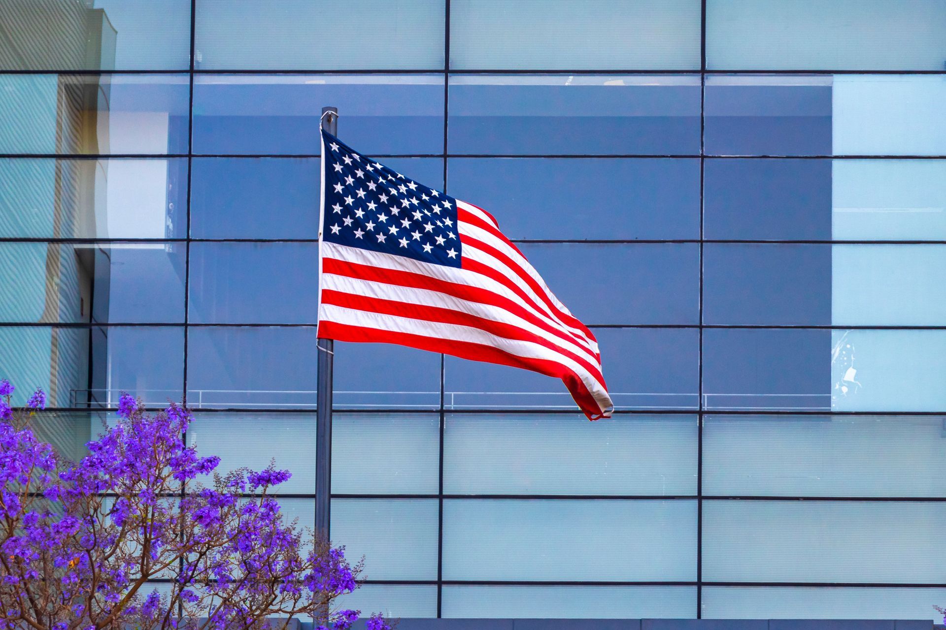 United States flag in front of skyscraper.