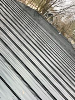 A close up of a metal roof with trees in the background.