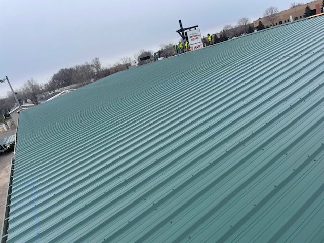A green metal roof is being installed on a building.