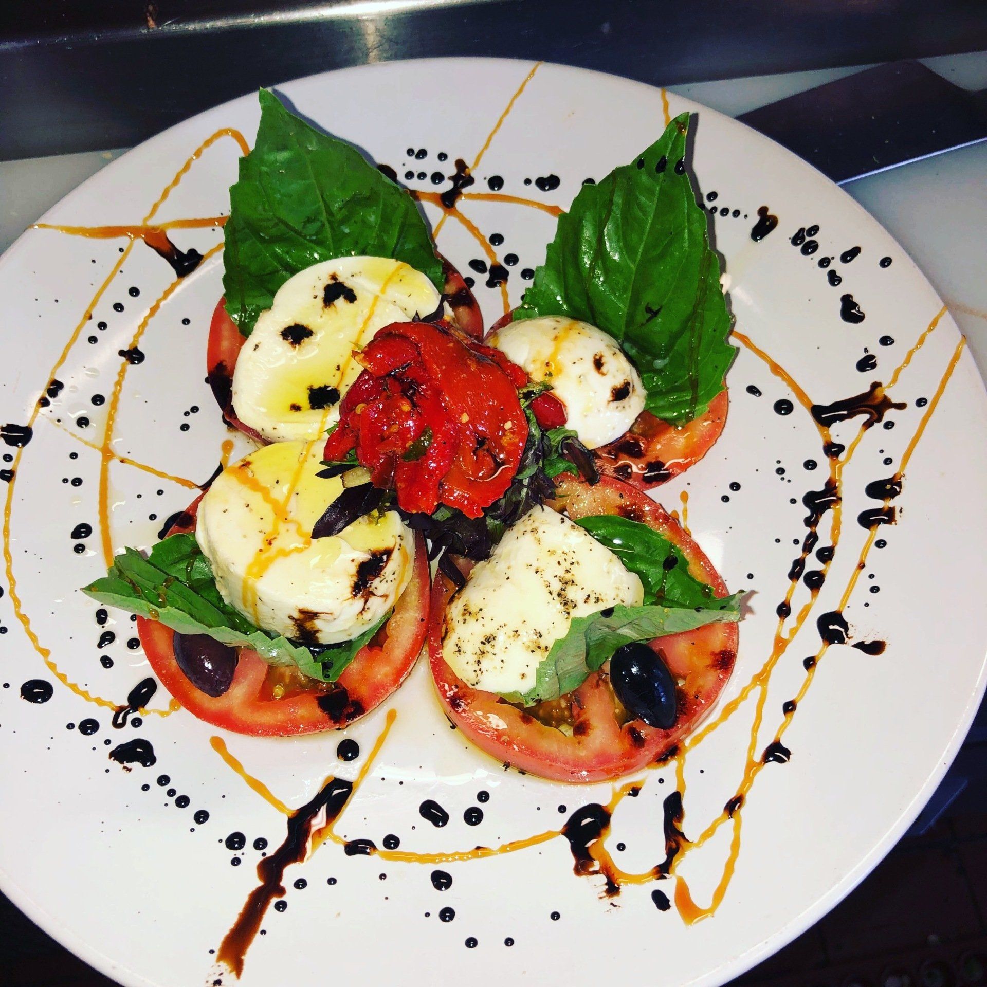 A white plate topped with tomatoes mozzarella and basil