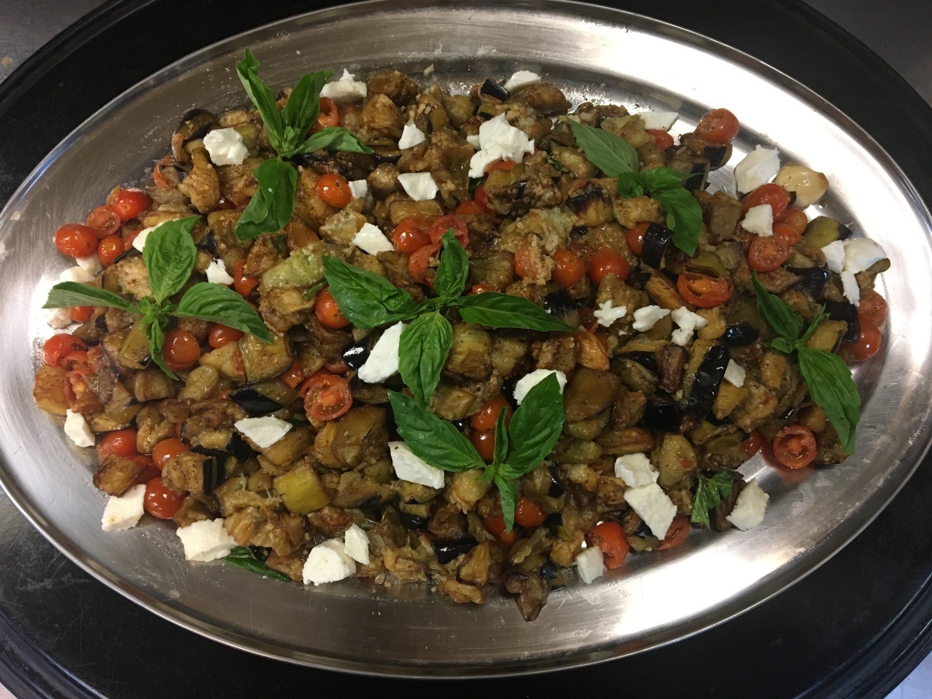 A silver plate topped with vegetables and cheese on a table.