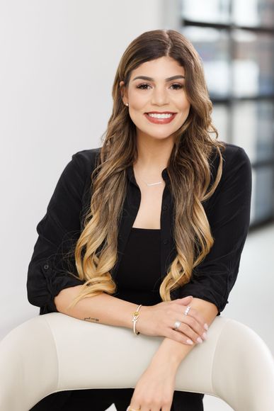 A woman is sitting in a chair with her arms crossed and smiling.