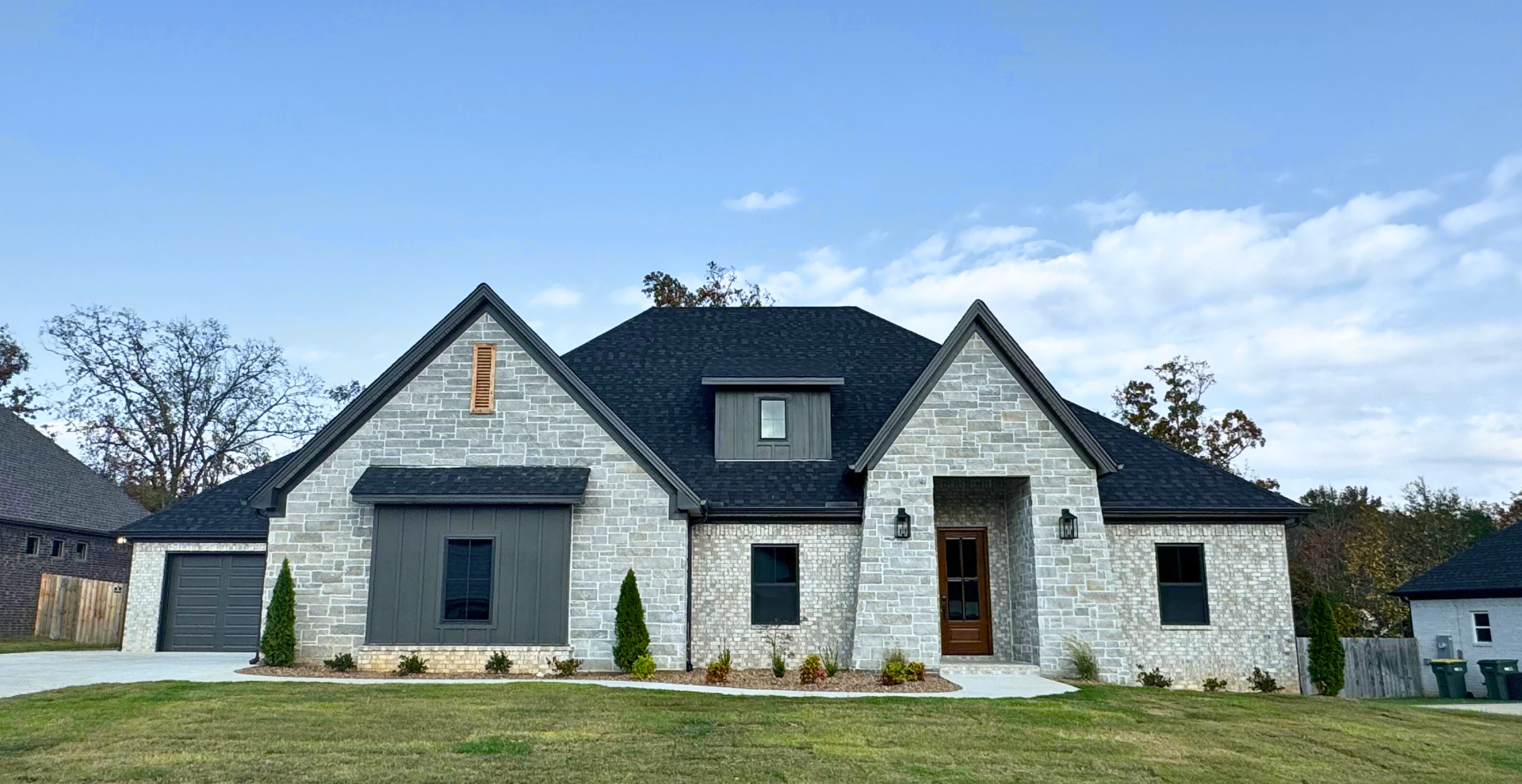 new construction home that has a dark roof and light brick also has a third car garage