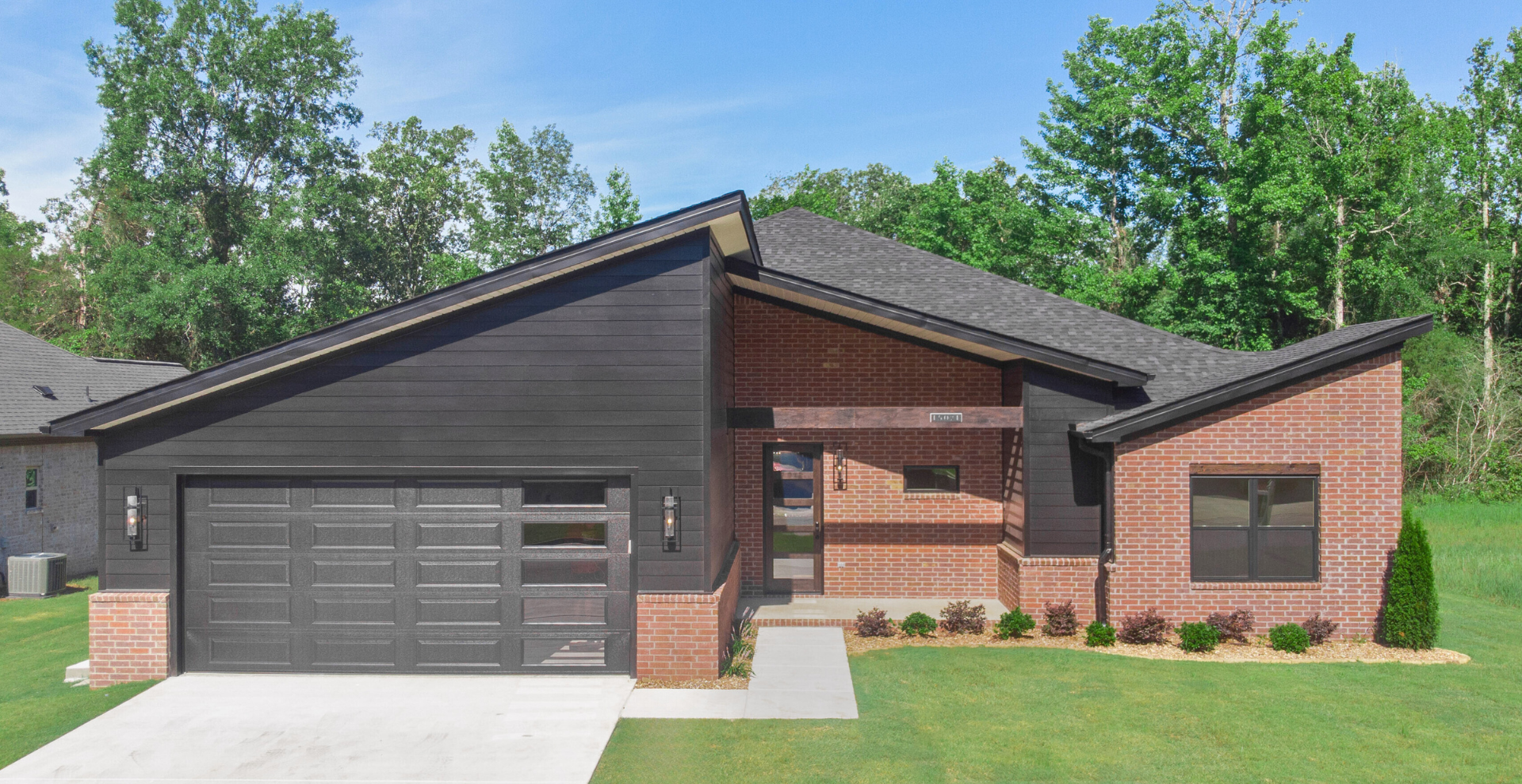 Modern new construction home with black garage door and dark brick exterior