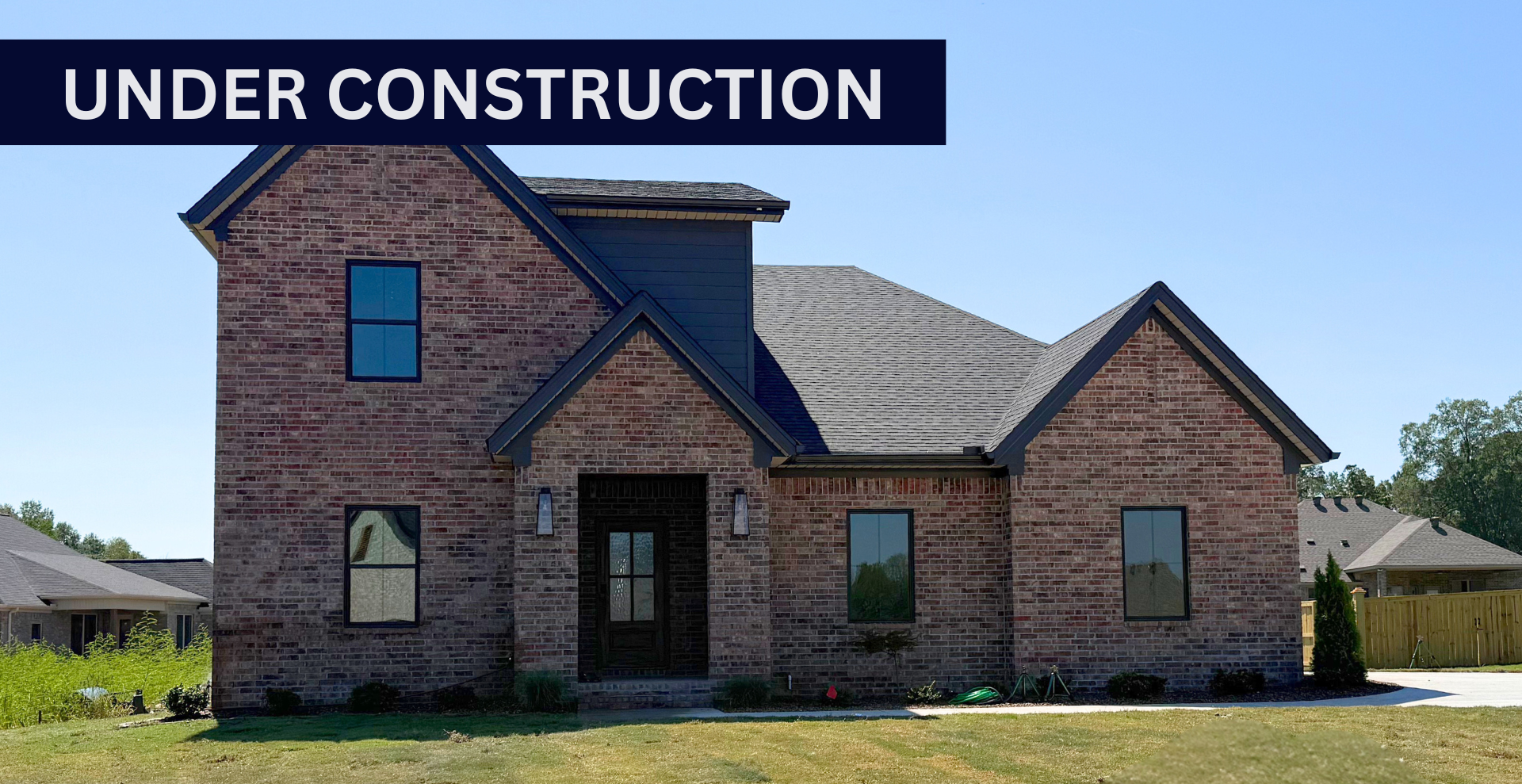 Simple custom home built by hines homes with dark brick and a white accent wall out front with a curved front porch