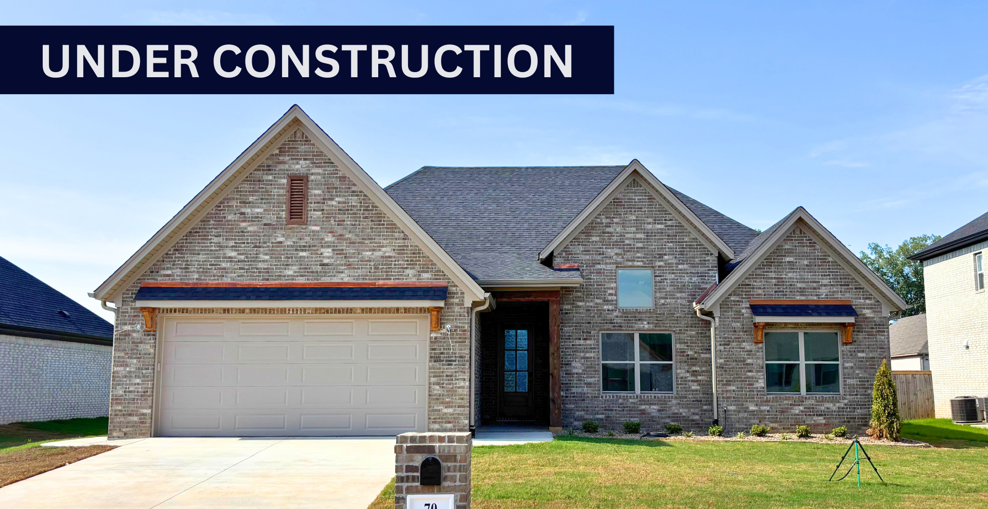Simple custom home built by hines homes with dark brick and a white accent wall out front with a curved front porch