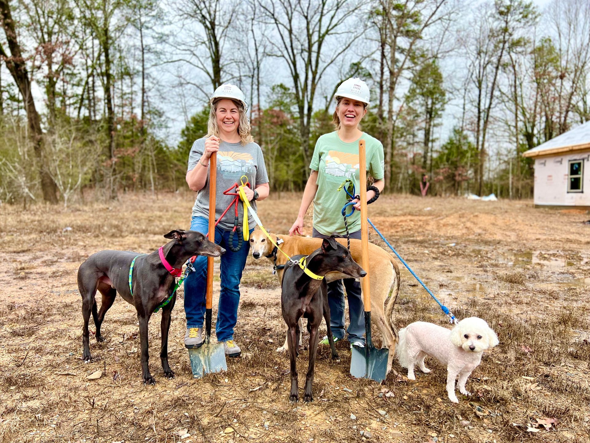 two women with dogs on leashes on a new construction home job site