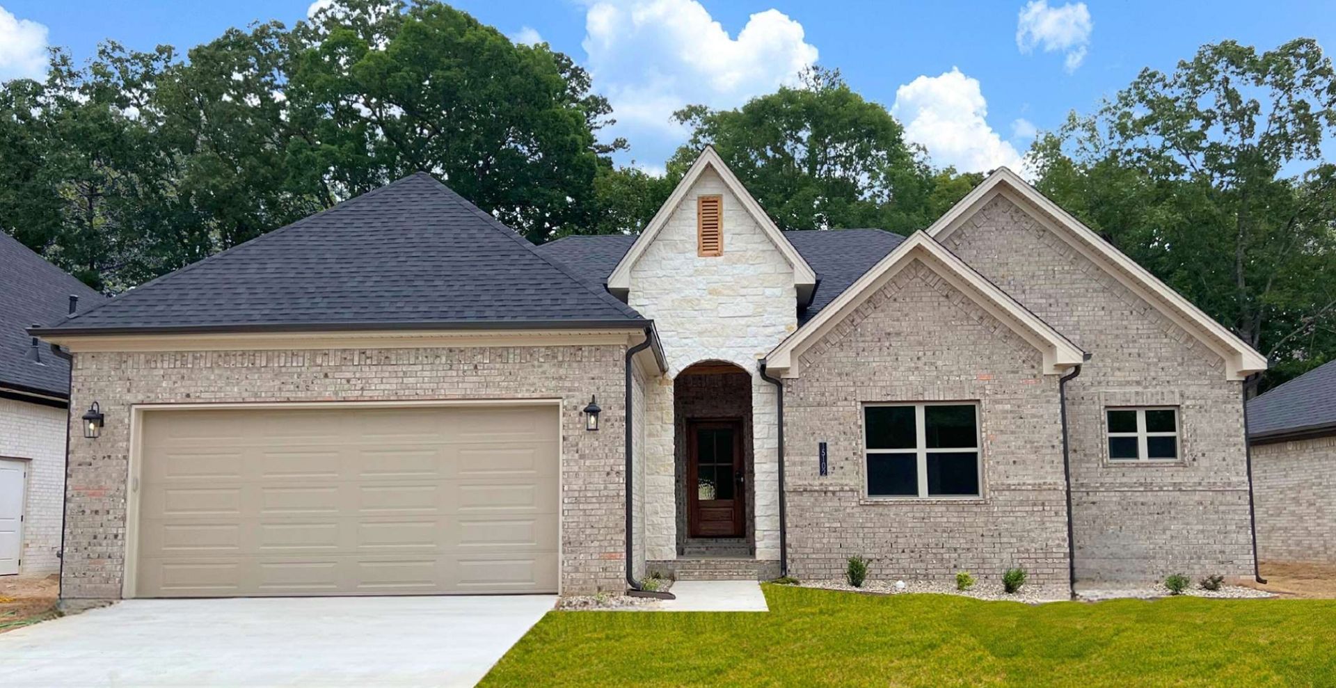 brand new construction home with brown garage door and beige brick
